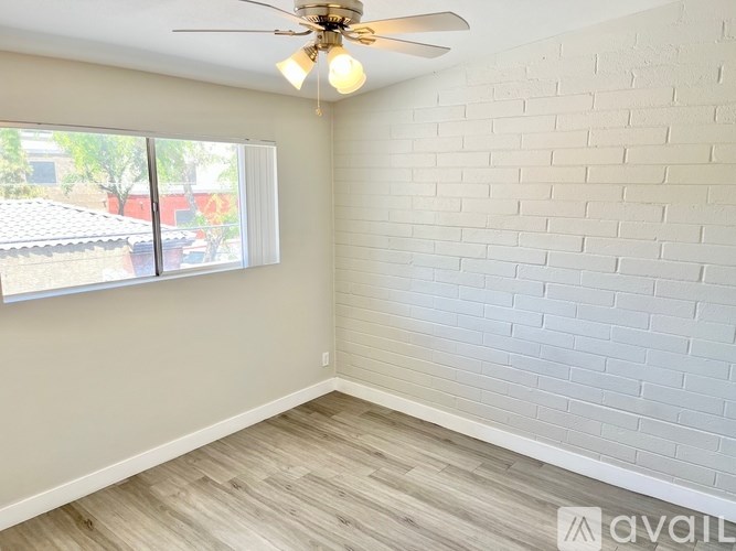 A room with a ceiling fan and a window overlooking a patio.