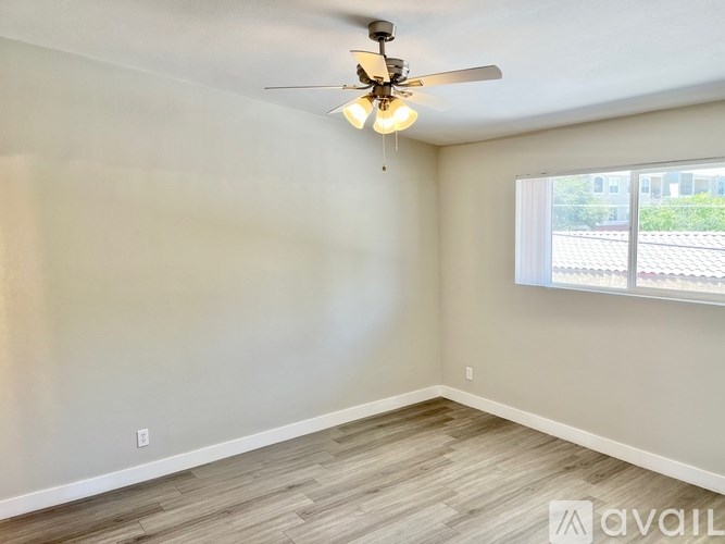 A room with a ceiling fan and a window with a view of a building outside.