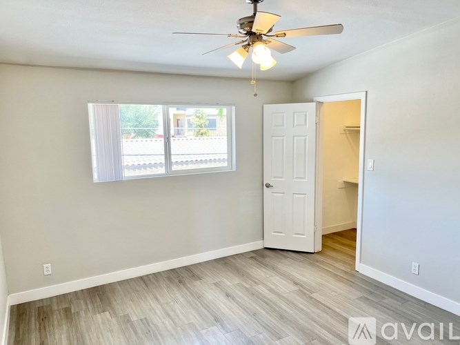 A room with a ceiling fan and a door leading to another room.