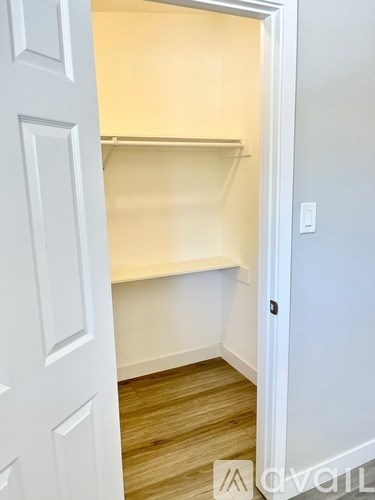 A white door is open to a room with a shelf and a light switch.