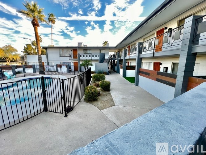 A view of a pool and apartment complex with a palm tree.