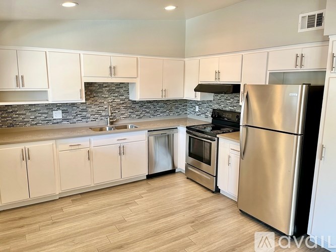 A kitchen with white cabinets and a stone backsplash.