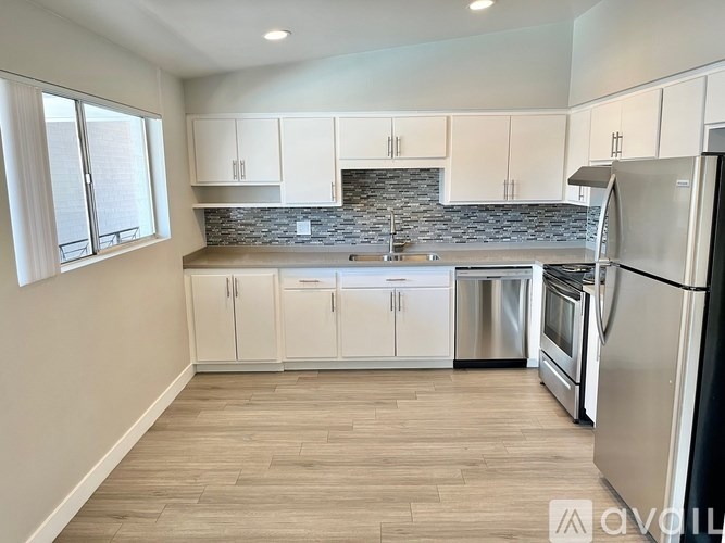 A kitchen with white cabinets and a stone backsplash.