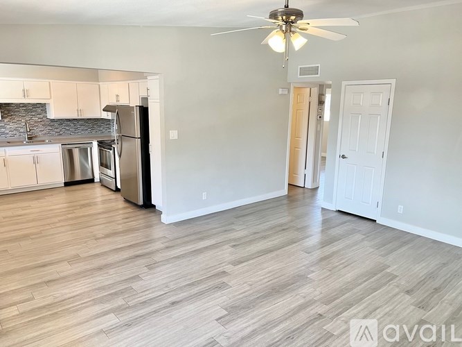 A spacious kitchen with white appliances and a fan.