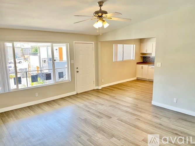 A spacious room with a ceiling fan and wooden flooring.