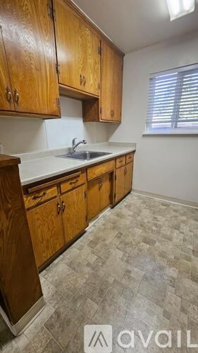 A kitchen with wooden cabinets and a tiled floor.