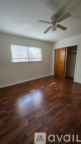 A room with a ceiling fan and wooden flooring.