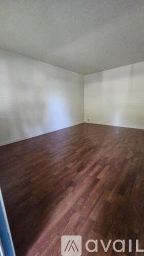 A room with wooden flooring and a white wall.