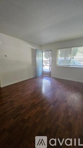 A room with wooden floors and a window with blinds.