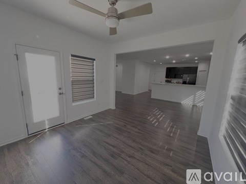 A spacious room with a ceiling fan and wooden flooring.