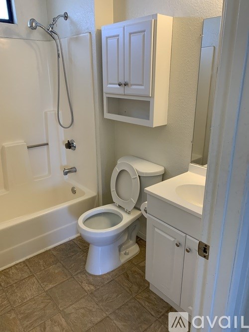 A white toilet in a bathroom with a white cabinet above it.