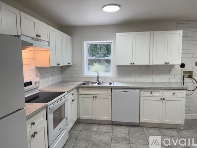 A kitchen with white cabinets and appliances.