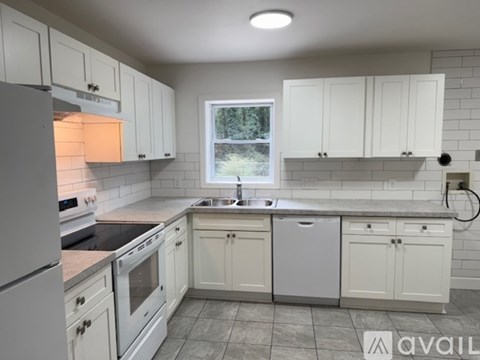 A kitchen with white cabinets and appliances.