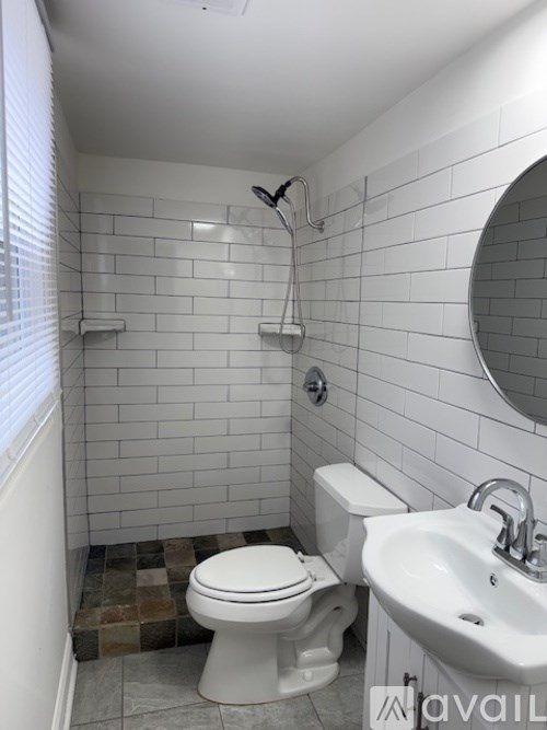 A white toilet sits next to a white sink in a bathroom with white tiles.