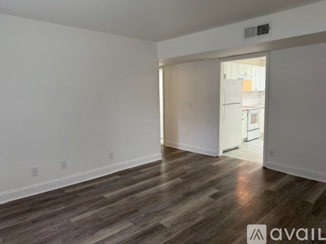 A room with wooden flooring and a doorway leading to another room.