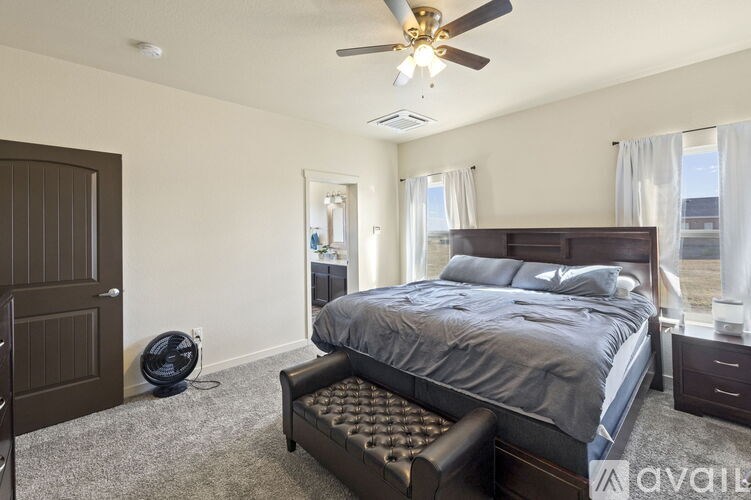A bedroom with a large bed and a ceiling fan.