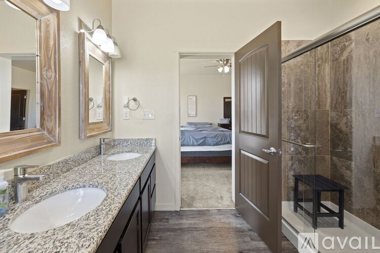 A bathroom with a marble countertop and a bed in the background.
