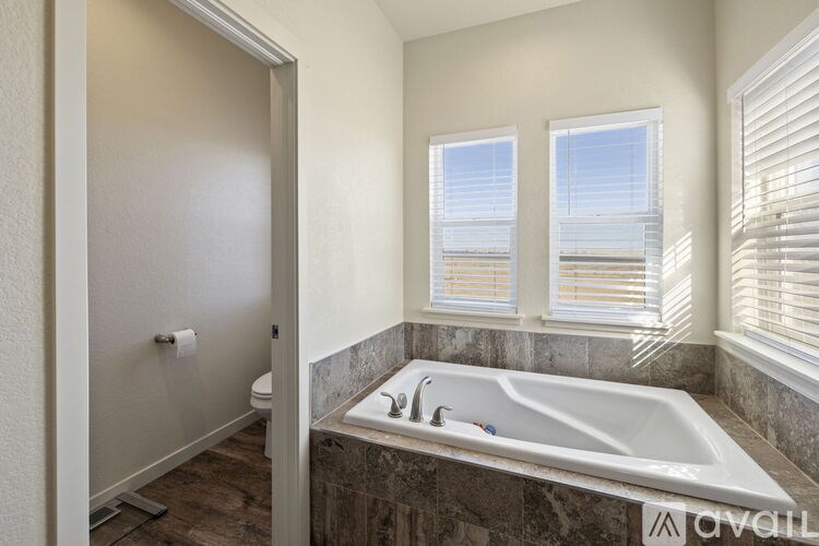 A bathroom with a large tub and a window with blinds.