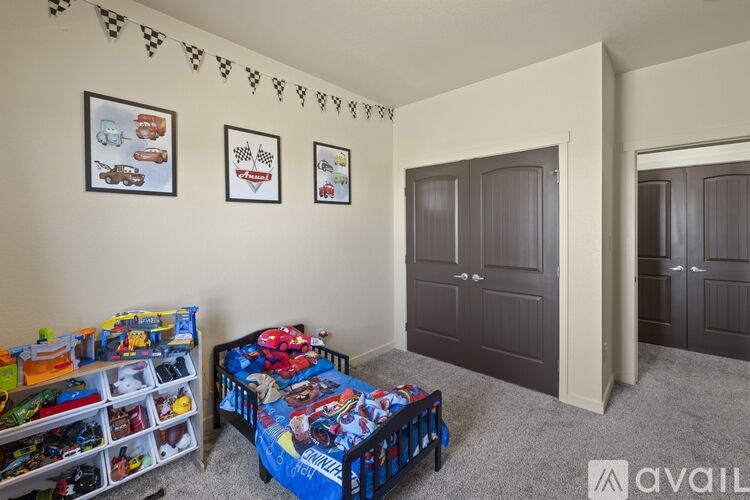 A child's bedroom with a bed, toy storage, and two framed pictures on the wall.