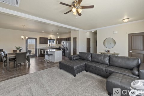 A spacious living room with a grey sofa and a ceiling fan.