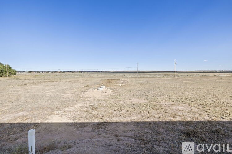 A vast, open, and barren landscape with a clear blue sky above.
