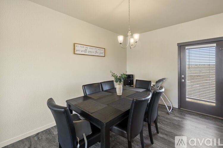 A dining room with a table and chairs and a quote on the wall.