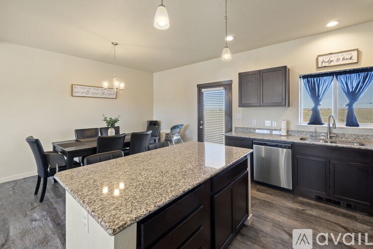 A kitchen with granite countertops and a dining area with chairs and a table.