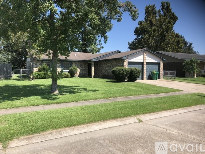 A house with a green lawn and trees in front.