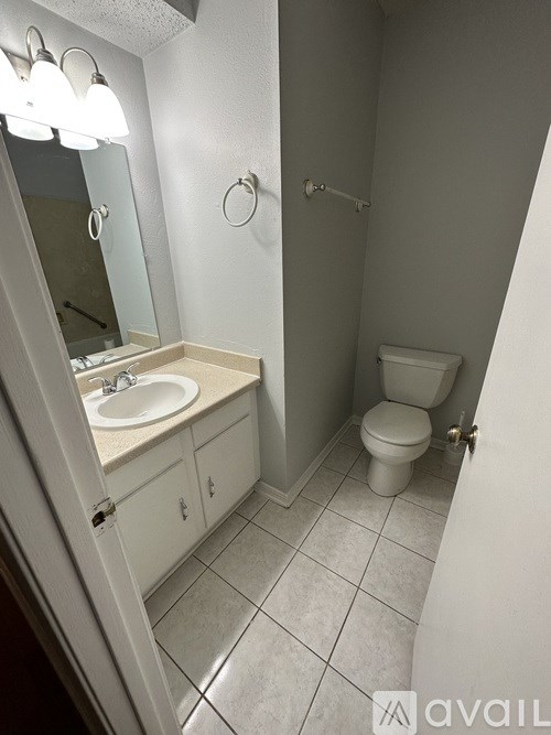A bathroom with a toilet, sink, and mirror.