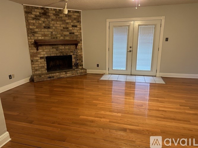 A room with a stone fireplace and wood flooring.
