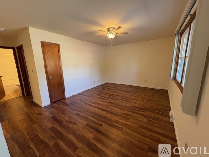 A room with wooden flooring and a ceiling fan.