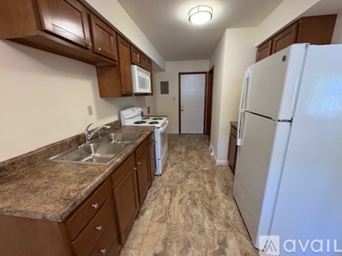 A kitchen with brown cabinets and a white refrigerator.