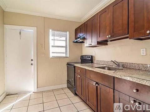 A kitchen with brown cabinets and a black dishwasher.