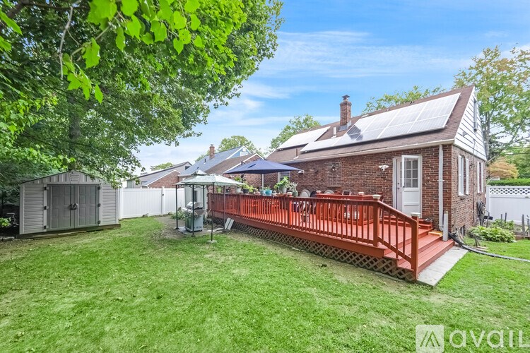 A house with a red deck and a tree in the foreground.