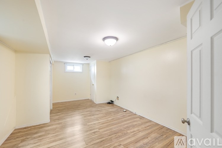 A room with wooden flooring and white walls, with a door on the right side.