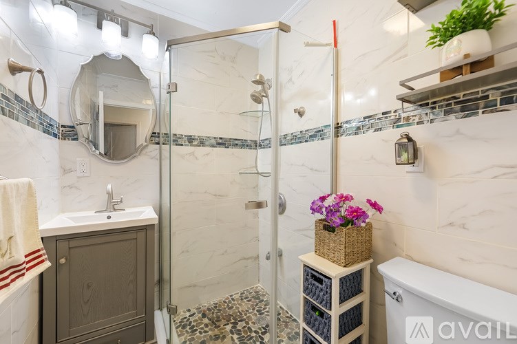 A bathroom with a marble wall and a shower with a glass door.