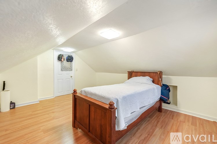 A bedroom with a bed, dresser, and a clock on the wall.