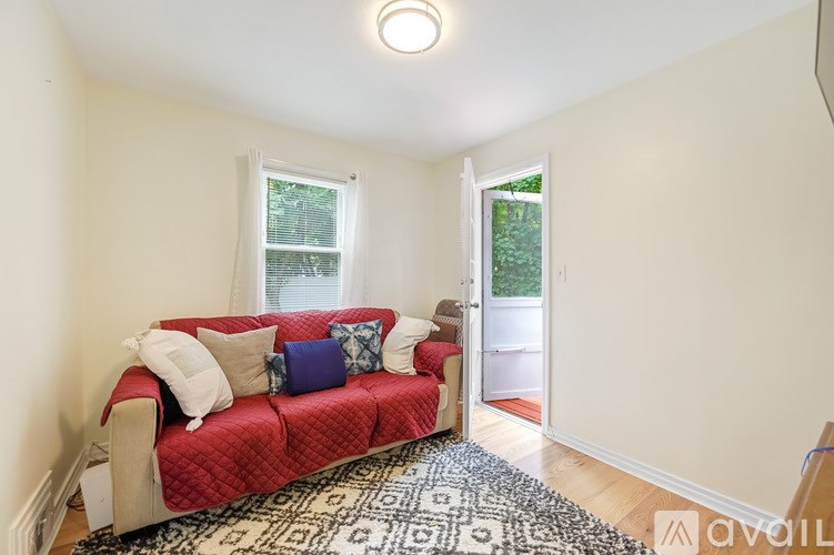 A living room with a red couch and a rug.