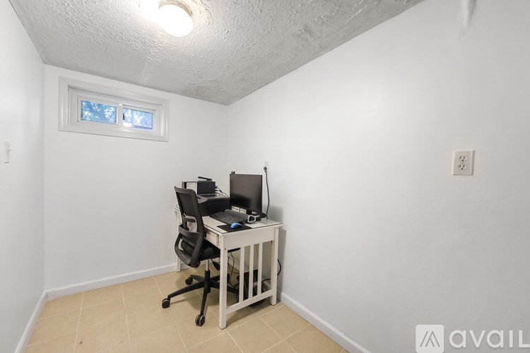 A small white desk with a computer and chair in a room with a window.