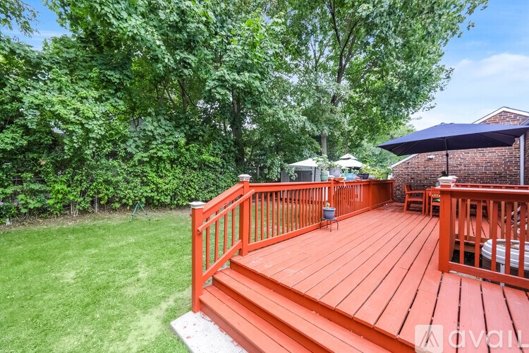 A wooden deck with a red railing and a white umbrella.