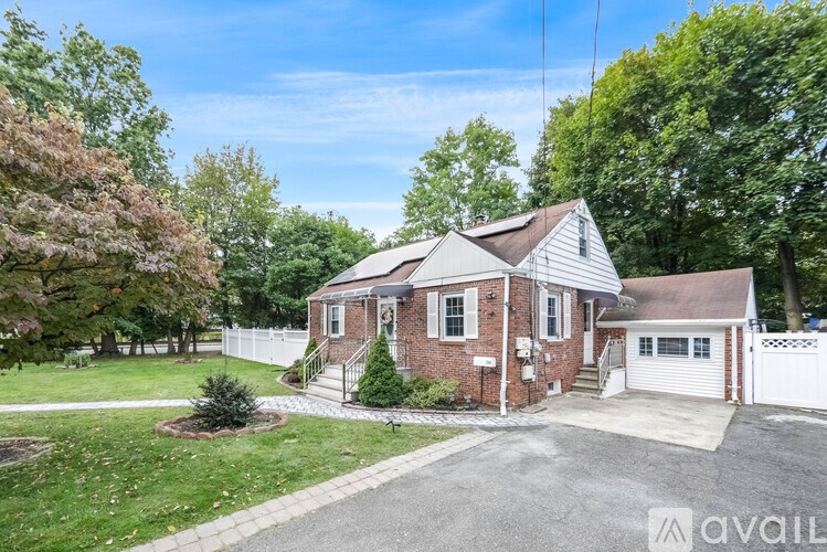 A house with a white fence and a driveway in front.
