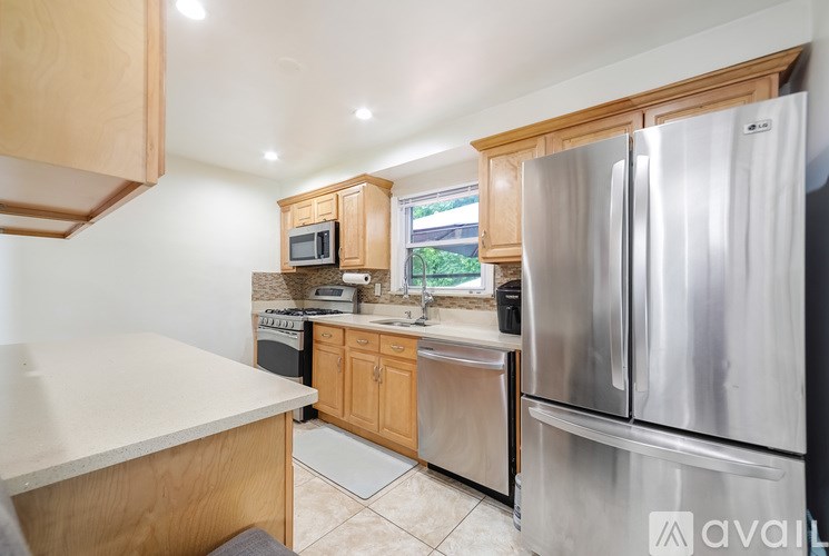 A kitchen with wooden cabinets and a stainless steel refrigerator.