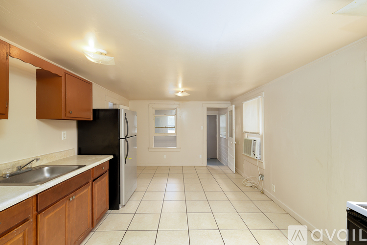A kitchen with a black refrigerator and wooden cabinets.