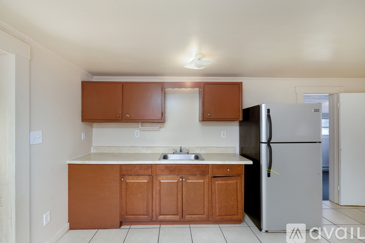 A kitchen with brown cabinets and a black refrigerator.