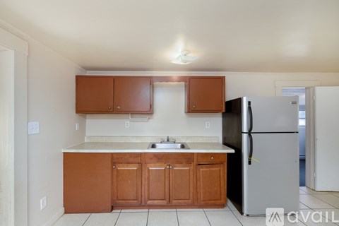A kitchen with brown cabinets and a black refrigerator.