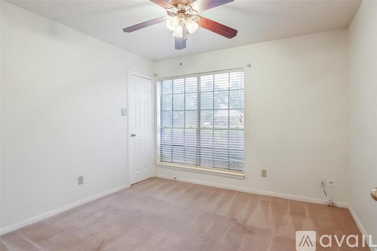 A room with a ceiling fan and a window with blinds.