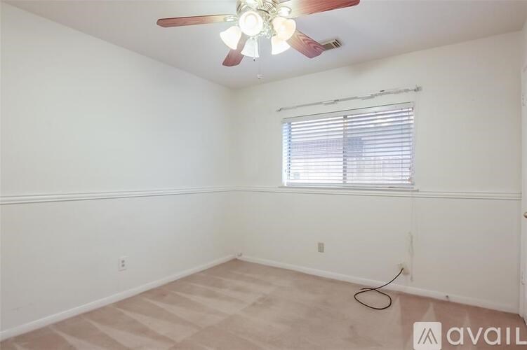 A room with a ceiling fan and a window with blinds.