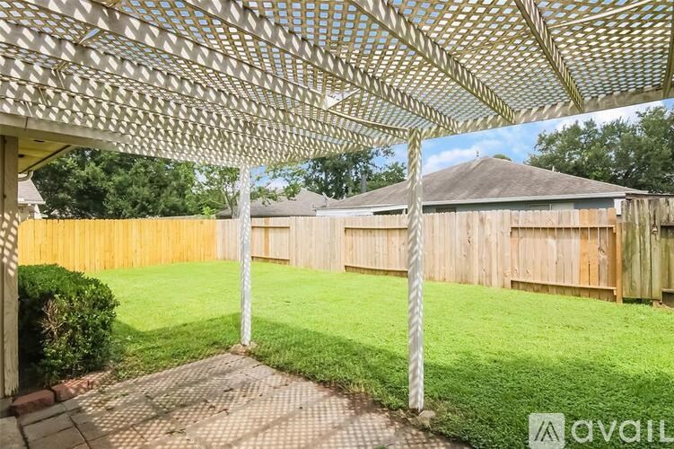 A backyard with a wooden fence and a trellis.