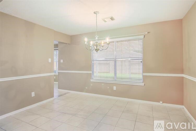 A room with a chandelier and a window with blinds.