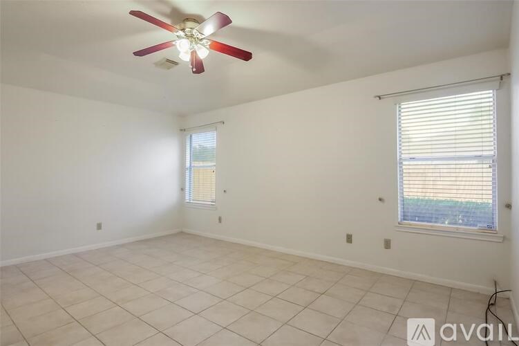 A room with a ceiling fan and two windows.